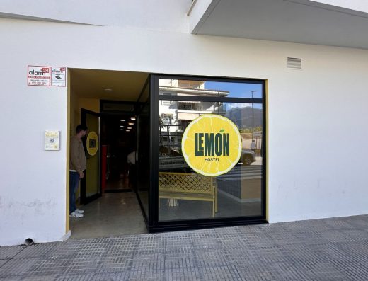 Imagen de la entrada al hostel. A la derecha hay un chico abriendo la puerta. A la derecha una cristalera con el nombre del hostel en el interior de un limón.