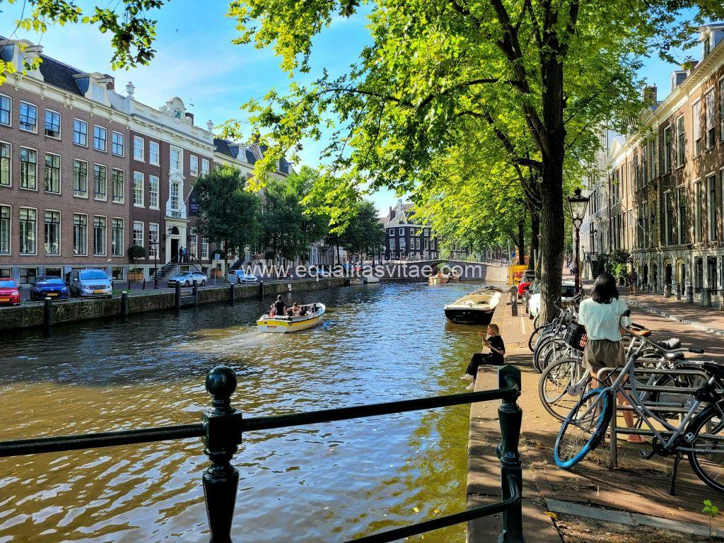 Imagen de un canal de Ámsterdam por el que van navegando dos pequeñas barcas