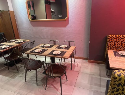 Imagen de una mesa cuadrada con pata central y 4 sillas. Está preparada con todos los elementos para recibir a los comensales.