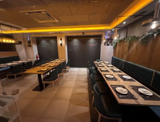 Imagen del interior del comedor con mesas de pata central separadas por un pasillo entre ellas.