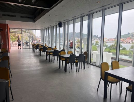 Imagen del interior del restaurante con una gran cristalera con vistas a Ribadesella.