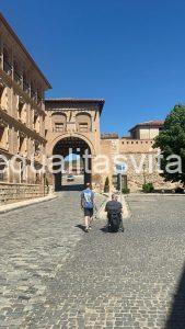 Imagen de dos personas acercándose al arco de entrada al casco histórico de Daroca, una de ellas va en silla de ruedas.