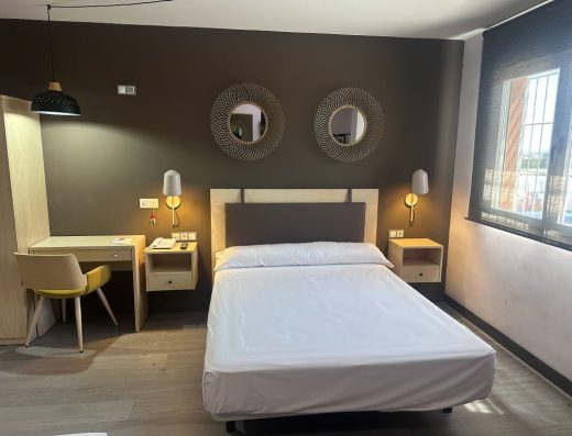 Imagen de una cama de matrimonio con dos pequeñas mesillas a cada lado.