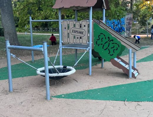 Imagen de la zona de juegos infantiles. Torre con acceso a través de rampa con escalón. De la torre sale un columpio tipo nido.