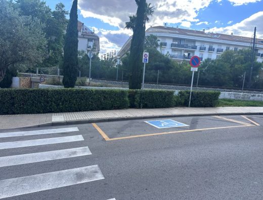 Imagen de una plaza de aparcamiento en línea reservada para personas con discapacidad, identificada con pictograma de accesibilidad en el pavimento.