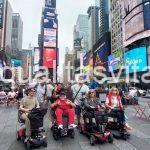 Imagen de un grupo de personas, algunas en silla de ruedas, posando para foto en la gran manzana.